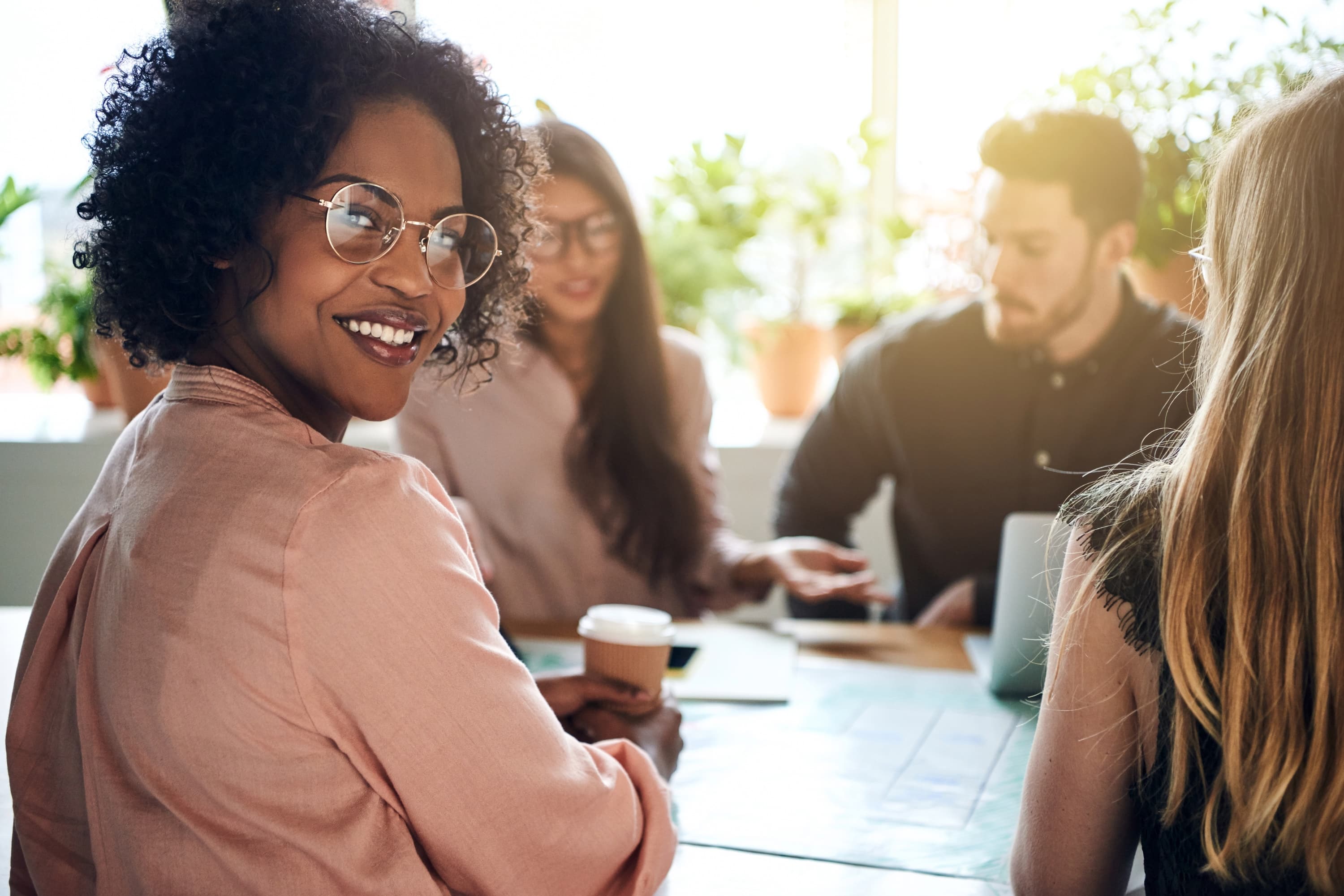 A Black woman smiling with colleagues during a collaborative meeting